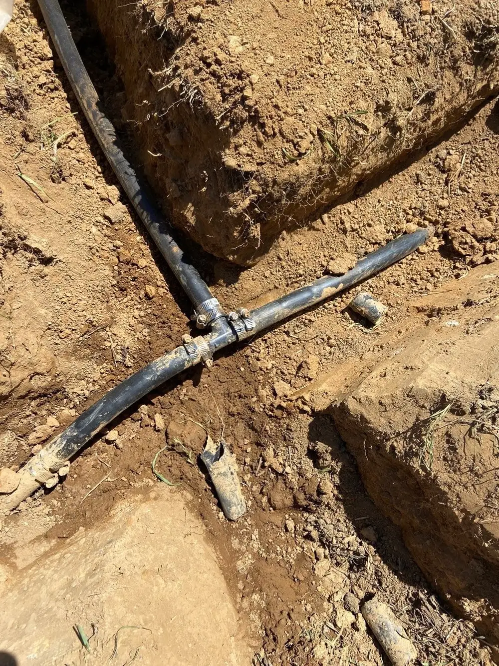 Black drain pipe tee junction in an open drainage trench, West Chester, PA
