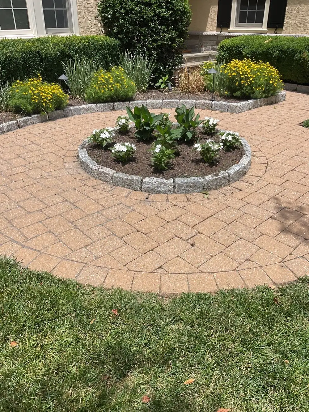 Circular paver patio with a center planting bed of hostas and white annuals